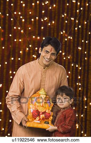 Father and son holding an idol of lord Ganesha View Large Photo Image Stock Photograph - Father and son holding an idol of lord Ganesha. Fotosearch