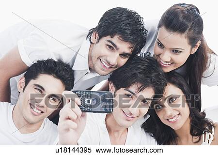 Stock Photography - Friends taking picture of themselves with a mobile phone. Fotosearch