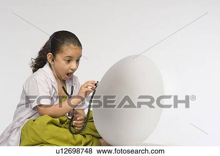 Stock Photo - Girl examining a egg with a stethoscope. Fotosearch
