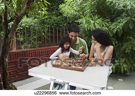 Stock Photograph - Girl playing chess with her parents. Fotosearch