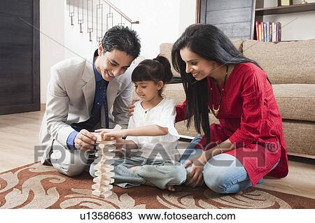 Girl playing Jenga with her parents View Large Photo Image Stock Image - Girl playing Jenga with her parents. Fotosearch