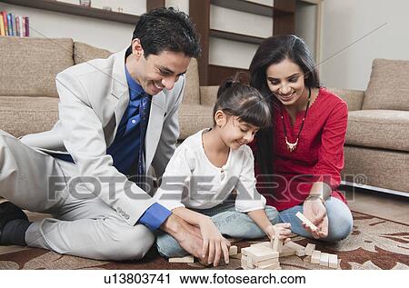 Stock Image - Girl playing Jenga with her parents. Fotosearch