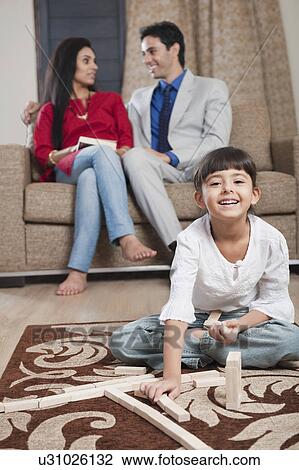 Girl playing Jenga with her parents sitting in the background View Large Photo Image Stock Image - Girl playing Jenga with her parents sitting in the background. Fotosearch