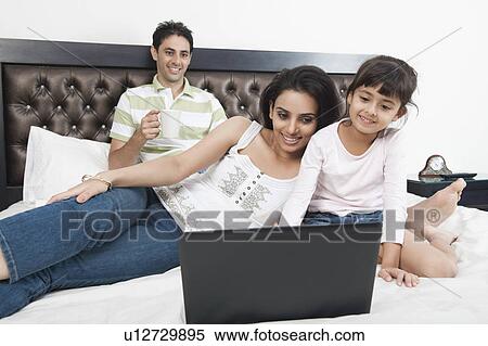 Girl using a laptop with her parents View Large Photo Image Stock Photography - Girl using a laptop with her parents. Fotosearch