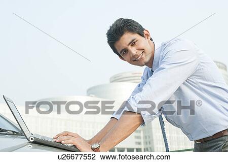 Stock Image - Happy businessman working on laptop, Gurgaon, Haryana, India. Fotosearch