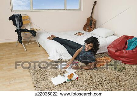 Stock Image - High angle view of a man eating pizza in the bedroom. Fotosearch
