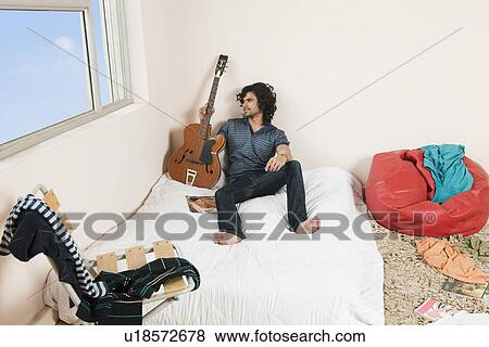 High angle view of a man holding a guitar in the bedroom View Large Photo Image Stock Photo - High angle view of a man holding a guitar in the bedroom. Fotosearch