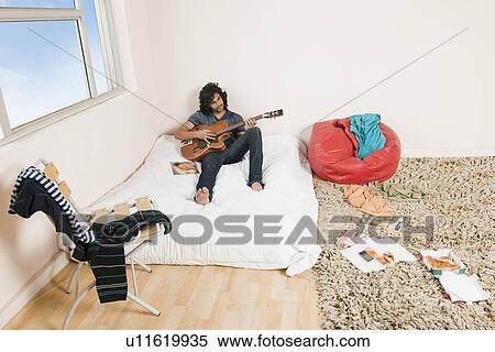 High angle view of a man playing a guitar in the bedroom View Large Photo Image Stock Photography - High angle view of a man playing a guitar in the bedroom. Fotosearch