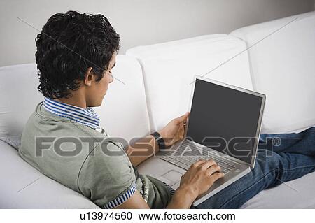 High angle view of a man sitting on a couch working on a laptop View Large Photo Image Stock Image - High angle view of a man sitting on a couch working on a laptop. Fotosearch