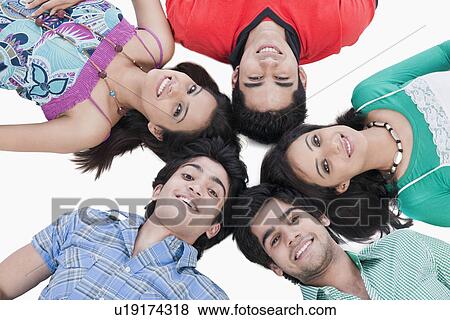 Stock Photo - High angle view of friends lying on the floor. Fotosearch