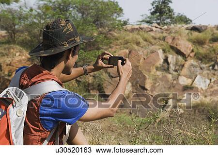 Stock Image - Hiker taking a picture with a mobile phone. Fotosearch