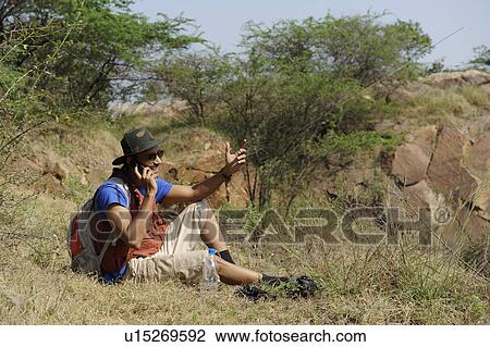 Hiker talking on a mobile phone View Large Photo Image Stock Image - Hiker talking on a mobile phone. Fotosearch