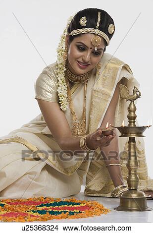 Indian woman in traditional clothing lighting an oil lamp View Large Photo Image Picture - Indian woman in traditional clothing lighting an oil lamp. Fotosearch