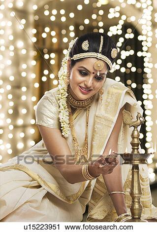 Indian woman in traditional clothing lighting an oil lamp View Large Photo Image Stock Image - Indian woman in traditional clothing lighting an oil lamp. Fotosearch