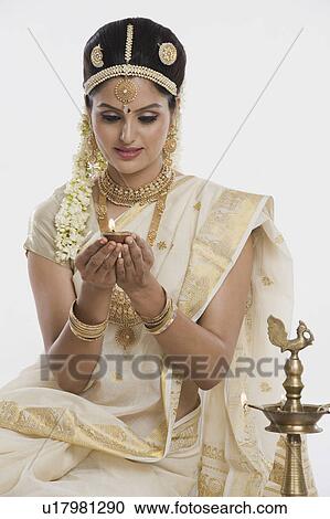 Stock Image - Indian woman in traditional clothing holding an oil lamp. Fotosearch