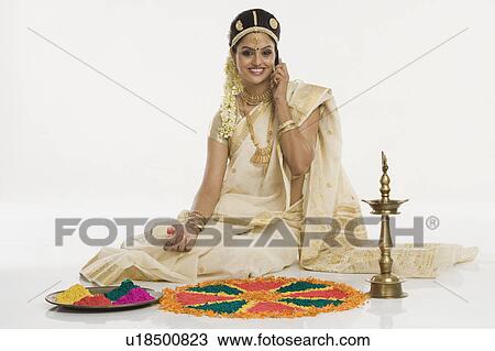 Indian woman in traditional clothing making rangoli and talking on a mobile phone View Large Photo Image Stock Image - Indian woman in traditional clothing making rangoli and talking on a mobile phone. Fotosearch