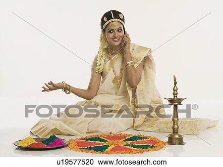 Indian woman in traditional clothing making rangoli and talking on a mobile phone View Large Photo Image Stock Image - Indian woman in traditional clothing making rangoli and talking on a mobile phone. Fotosearch