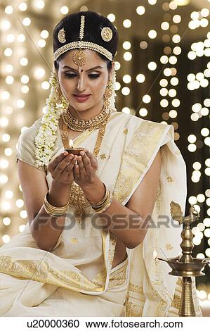 Stock Image - Indian woman in traditional clothing holding an oil lamp. Fotosearch
