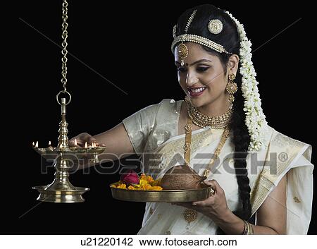 Indian woman in traditional clothing lighting an oil lamp View Large Photo Image Stock Image - Indian woman in traditional clothing lighting an oil lamp. Fotosearch