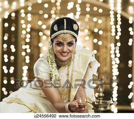 Indian woman in traditional clothing lighting an oil lamp View Large Photo Image Stock Image - Indian woman in traditional clothing lighting an oil lamp. Fotosearch