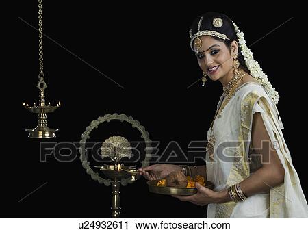 Indian woman in traditional clothing lighting an oil lamp View Large Photo Image Stock Image - Indian woman in traditional clothing lighting an oil lamp. Fotosearch