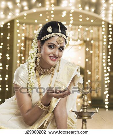 Indian woman in traditional clothing lighting an oil lamp View Large Photo Image Stock Image - Indian woman in traditional clothing lighting an oil lamp. Fotosearch