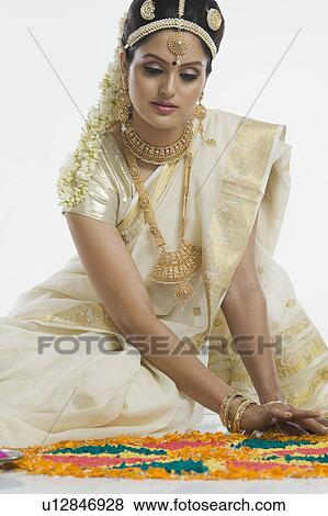 Stock Photo - Indian woman in traditional clothing making rangoli at Durga festival. Fotosearch