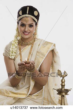 Indian woman in traditional clothing praying with an oil lamp View Large Photo Image Stock Photo - Indian woman in traditional clothing praying with an oil lamp. Fotosearch