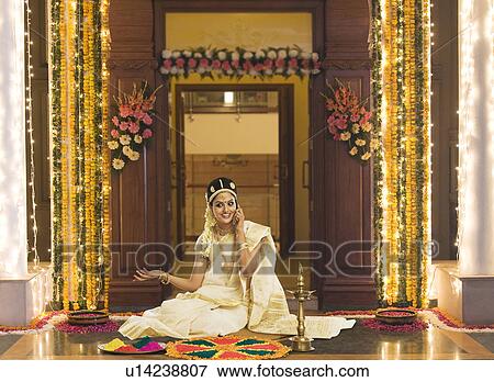 Stock Photo - Indian woman in traditional clothing making rangoli and talking on a mobile phone. Fotosearch