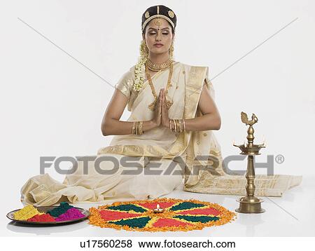 Stock Photo - Indian woman in traditional clothing praying at Durga puja festival. Fotosearch