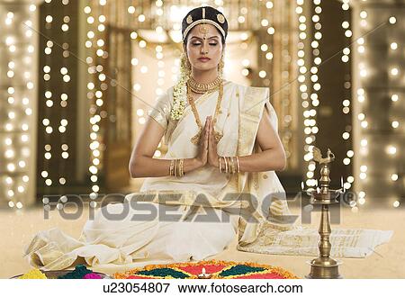 Stock Photo - Indian woman in traditional clothing praying at Durga puja festival. Fotosearch