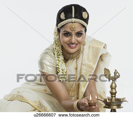 Indian woman in traditional clothing lighting an oil lamp View Large Photo Image Stock Photo - Indian woman in traditional clothing lighting an oil lamp. Fotosearch