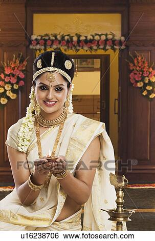 Indian woman in traditional clothing praying with an oil lamp View Large Photo Image Stock Photograph - Indian woman in traditional clothing praying with an oil lamp. Fotosearch