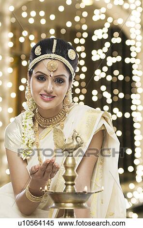 Indian woman in traditional clothing lighting an oil lamp View Large Photo Image Stock Photography - Indian woman in traditional clothing lighting an oil lamp. Fotosearch