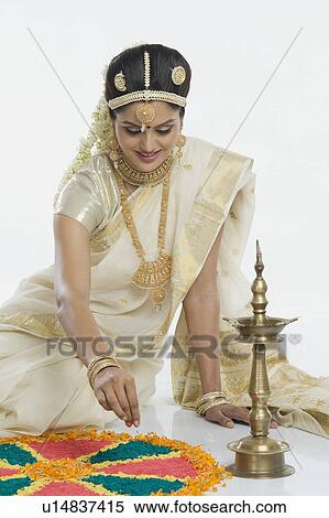 Stock Photography - Indian woman in traditional clothing making rangoli at Durga festival. Fotosearch