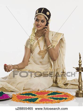Stock Photography - Indian woman in traditional clothing making rangoli and talking on a mobile phone. Fotosearch