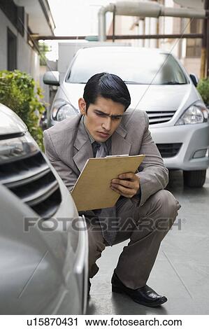 Stock Image - Insurance adjuster inspecting a car. Fotosearch
