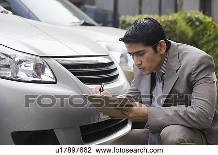 Stock Image - Insurance adjuster inspecting a car. Fotosearch