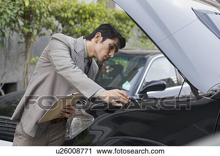 Stock Image - Insurance adjuster inspecting a car. Fotosearch