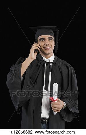 Male graduate holding diploma and talking on a mobile phone View Large Photo Image Stock Image - Male graduate holding diploma and talking on a mobile phone. Fotosearch