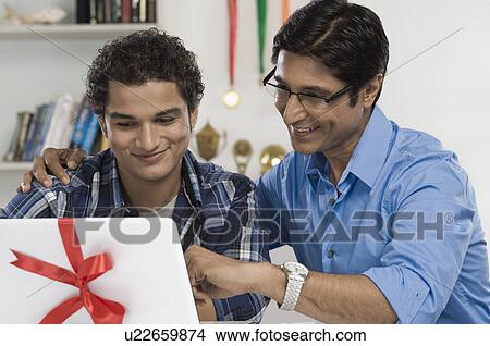 Man and his son looking at a new laptop View Large Photo Image Picture - Man and his son looking at a new laptop. Fotosearch