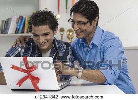 Stock Image - Man and his son looking at a new laptop. Fotosearch