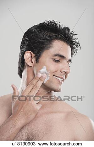 Stock Image - Man applying moisturizer on his face. Fotosearch