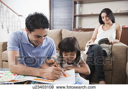 Stock Photo - Man assisting his daughter in drawing. Fotosearch