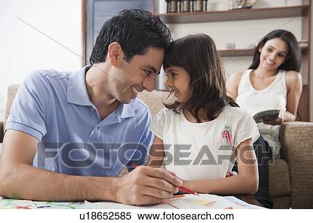 Stock Photography - Man assisting his daughter in drawing. Fotosearch