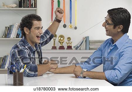 Stock Image - Man celebrating after defeat his father in arm wrestling. Fotosearch