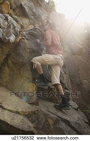 Stock Image - Man climbing on rocks. Fotosearch