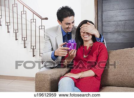 Man covering his wife's eyes to give a surprise gift View Large Photo Image Stock Photo - Man covering his wife's eyes to give a surprise gift. Fotosearch