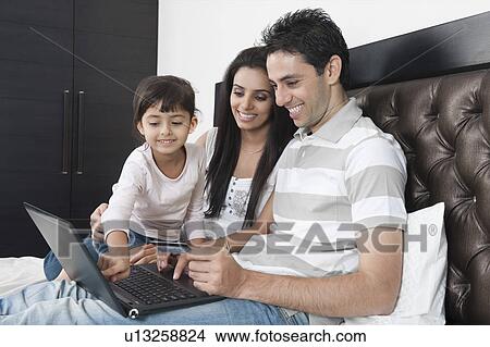 Picture - Man doing online shopping with his family. Fotosearch
