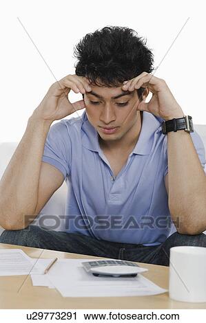Stock Image - Man doing paperwork at home and thinking. Fotosearch